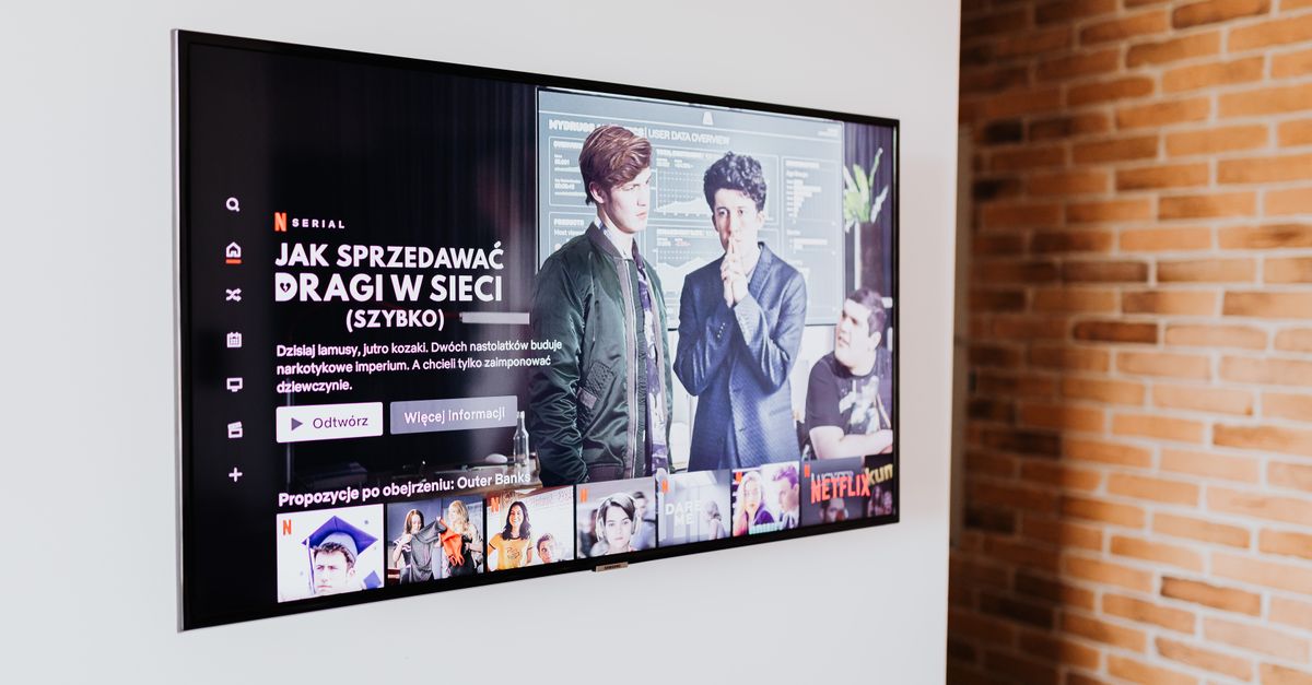 Télévision connectée diffusant une série dans un salon moderne avec mur en briques apparentes.