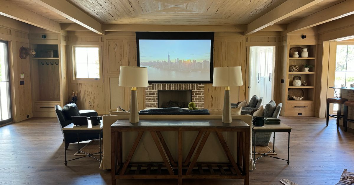 Salon moderne avec écran de projection, fauteuils confortables et décoration en bois chaleureux